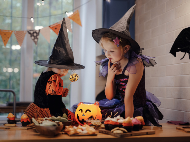 Two children wearing clothing and sitting at a table with food, A Guide to Halloween Candy: Tricks to Keep Your Family’s Teeth Healthy