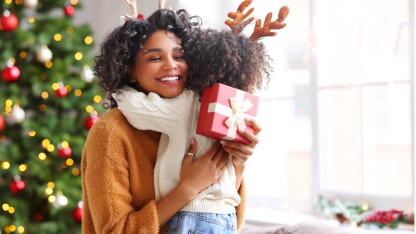 A person hugging a child with a gift, Embrace the Joy: 12 Dental Tips for a Twinkling Holiday Smile