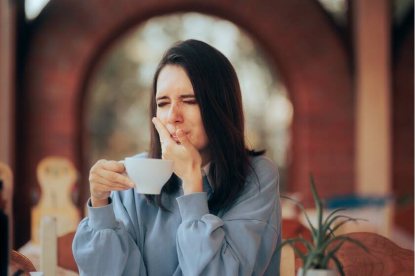 A person holding their mouth after drinking a cup of tea, Understanding Tooth Sensitivity: Causes, Symptoms, and Treatment Options