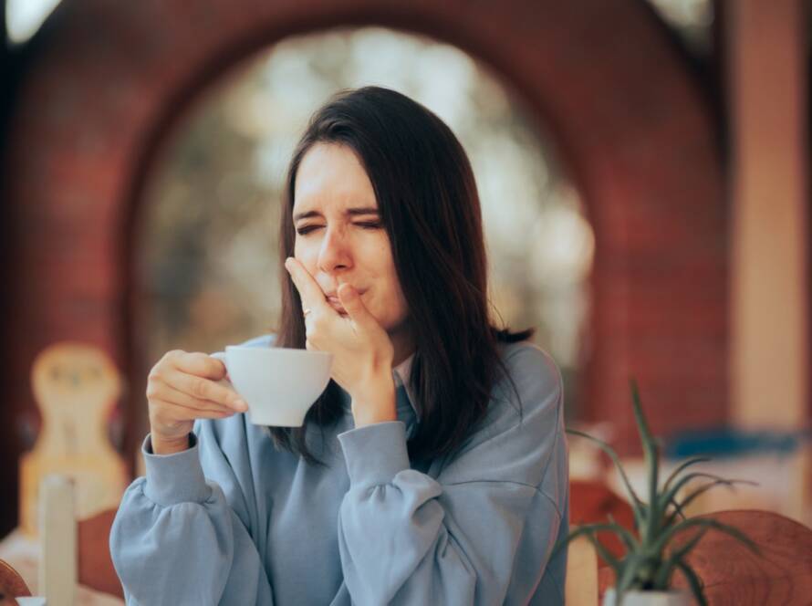 A person holding their mouth after drinking a cup of tea, Understanding Tooth Sensitivity: Causes, Symptoms, and Treatment Options